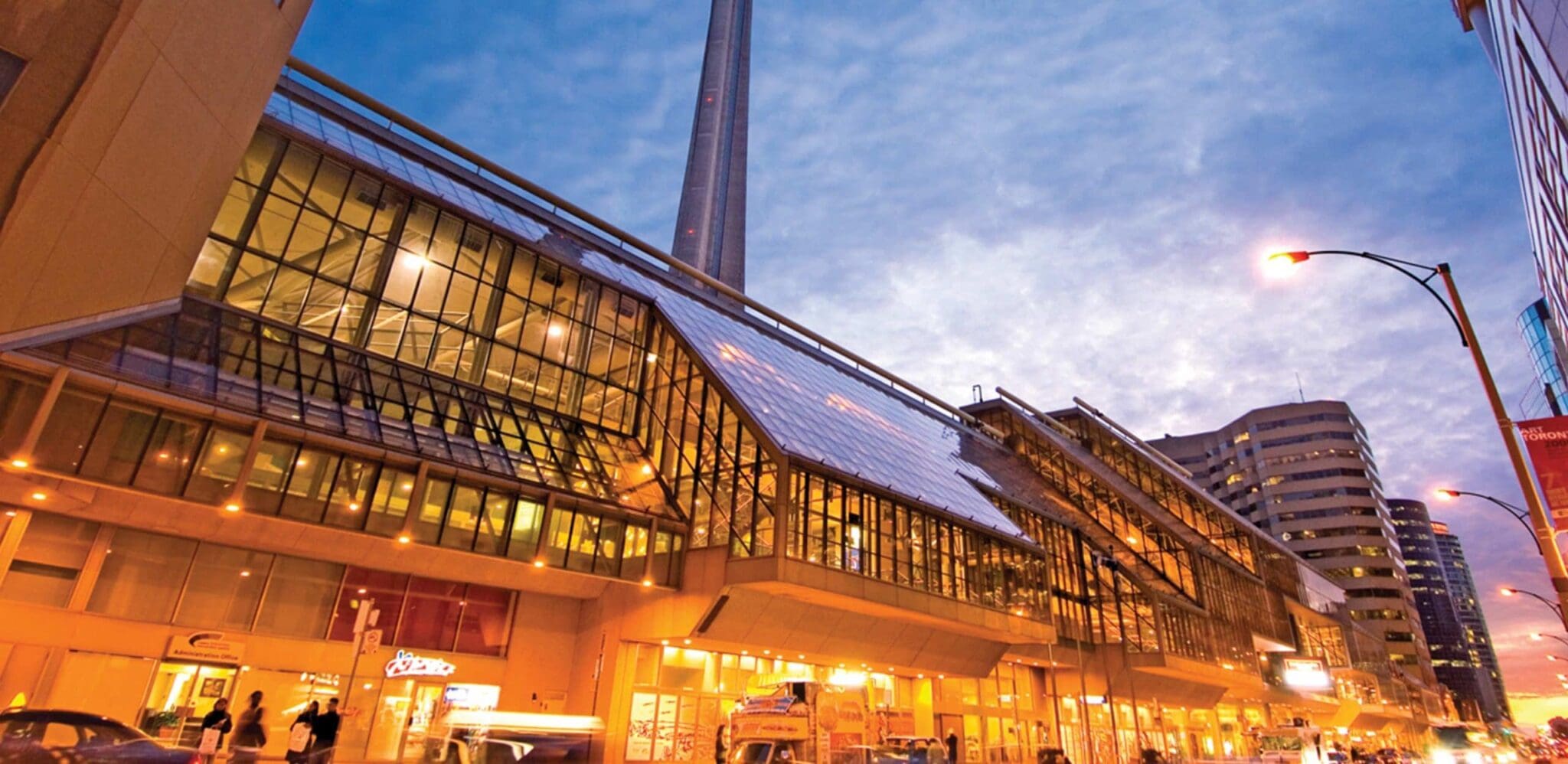 Exterior side view of the Metro Toronto Convention Centre at sunset. CN Tower in the background.