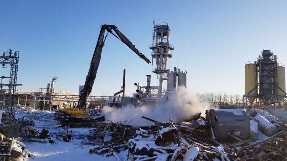 Ethanol plant decommissioning project featuring a high reach machine dismantling a tower stack in the centre of the plant