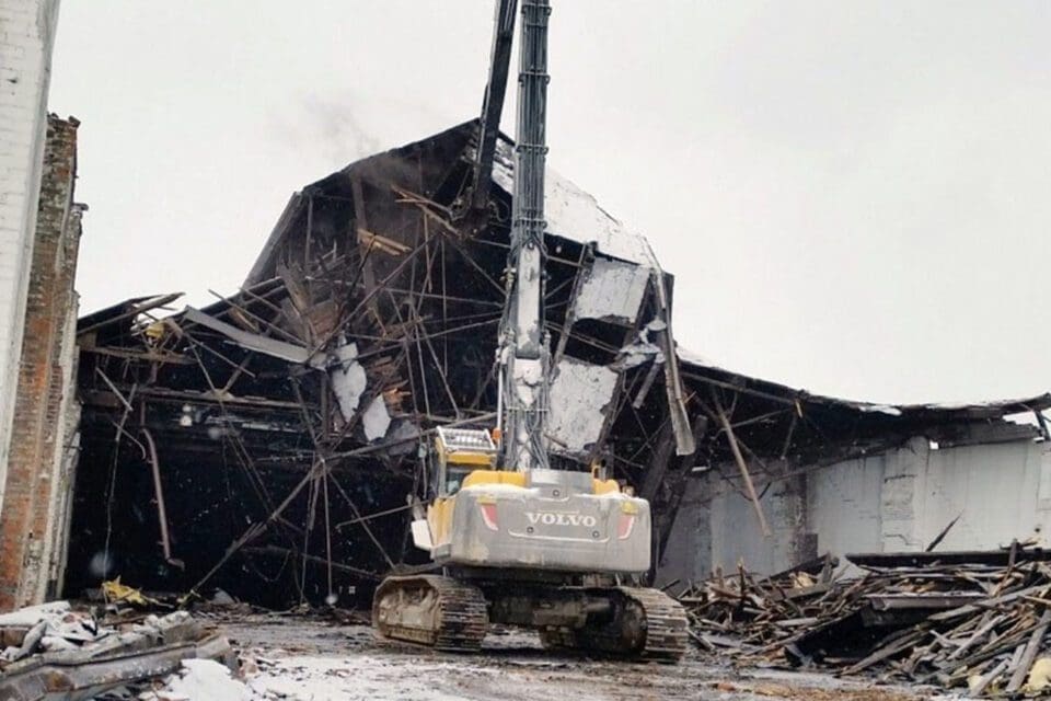 Large scale, industrial demolition using a high reach machine.