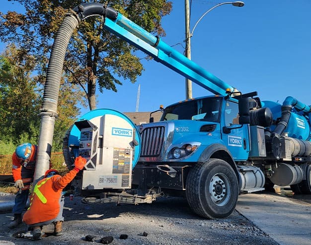 Hydrovac sewer flushing equipment clearing debris from underground pipes.