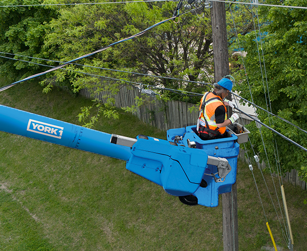 YORK1 utilities technician repairing lies while standing in an aerial bucket truck