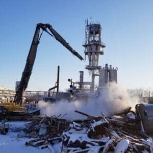 Ethanol plant decommissioning project featuring a high reach machine dismantling a tower stack in the centre of the plant