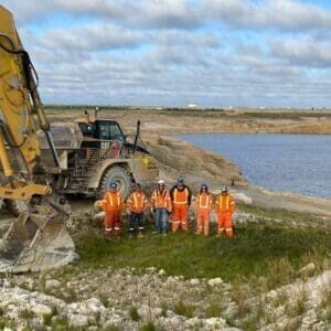 Mine decommissioning and reclamation project with proud employees lined up in front of earthworks equipment